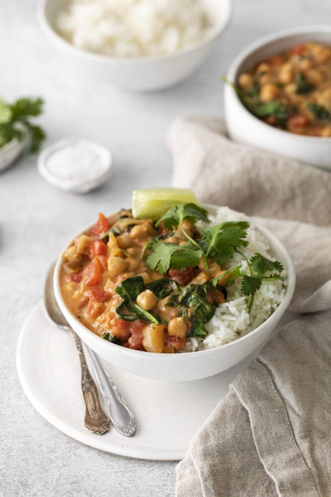 picture of vegan chickpea curry in a bowl with rice, a slice of lime, and cilantro on top 