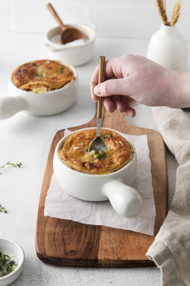 picture of an individual chicken pot pie in a white ramekin and a spoon dipping in 