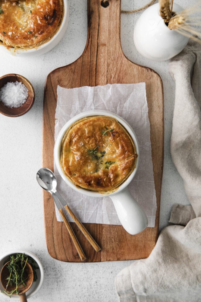 picture of an individual chicken pot pie in a white ramekin topped with thyme