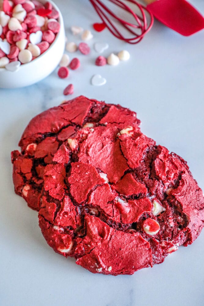 picture of red velvet cookie on a white plate surrounded by white and red baking chips