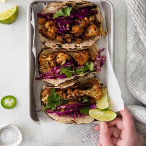 Easy vegan cauliflower tacos with lime wedges on a tray.