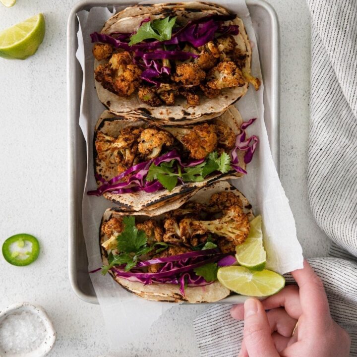 Easy vegan cauliflower tacos with lime wedges on a tray.