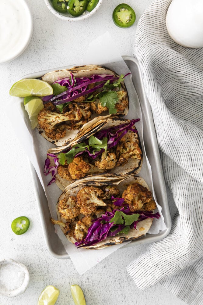 picture of cauliflower tacos with vegan crema and slaw in a metal tray