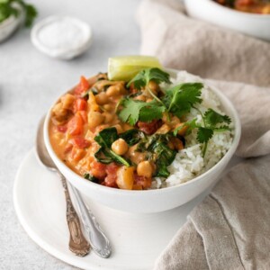 picture of vegan chickpea curry in a bowl with rice, a slice of lime, and cilantro on top