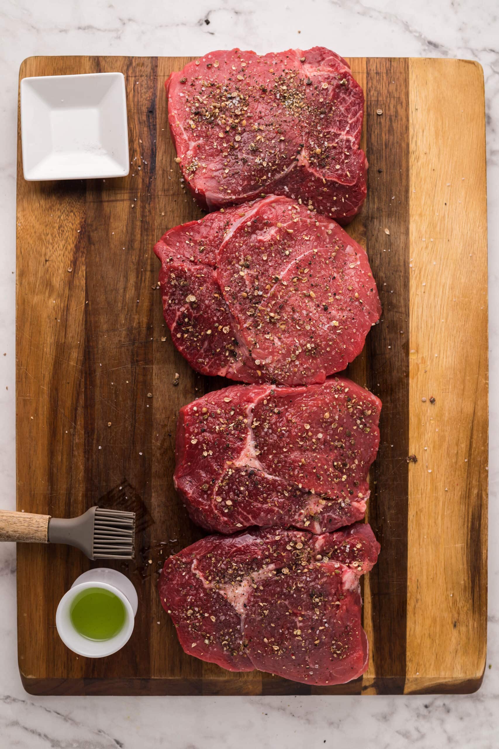 Parmesan crusted steak on a cutting board with olive oil and a fork.