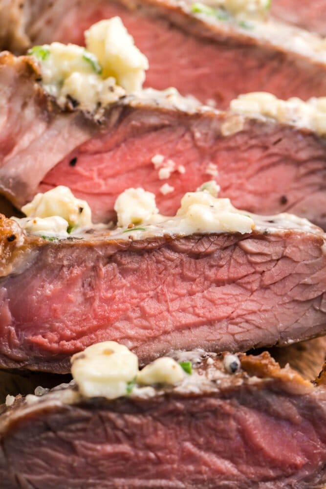 picture of sliced new york strip steak with blue cheese butter on top 