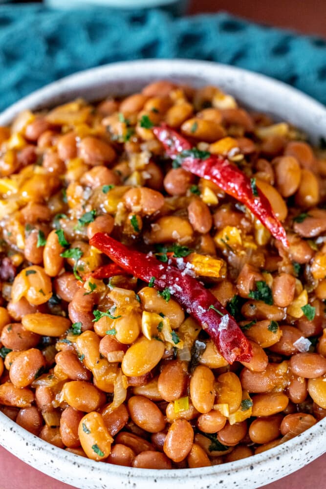 spicy beans in a bowl with salt, cilantro, and chilies on top