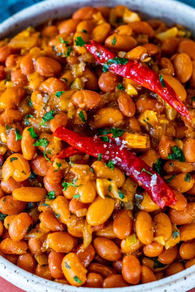 garlicky beans with seasoning, salt, and chilies in a white bowl 