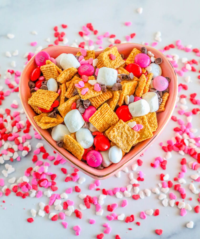 heart shaped bowl with snack mix made of marshmallows, pink m&ms, sprinkles,  and chocolate chips