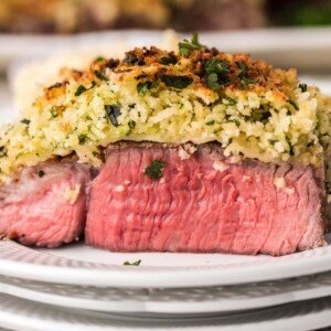 parmesan encrusted steak on a white plate in front of an air fryer
