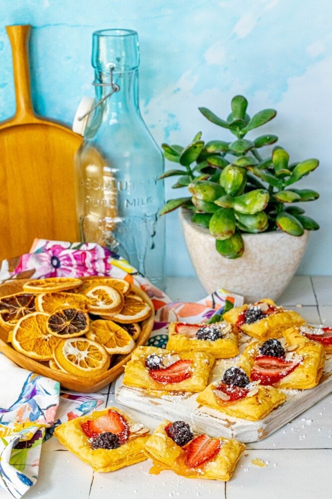 picture of lemon tart with a strawberry, blackberry, and almonds on top on a white cutting board