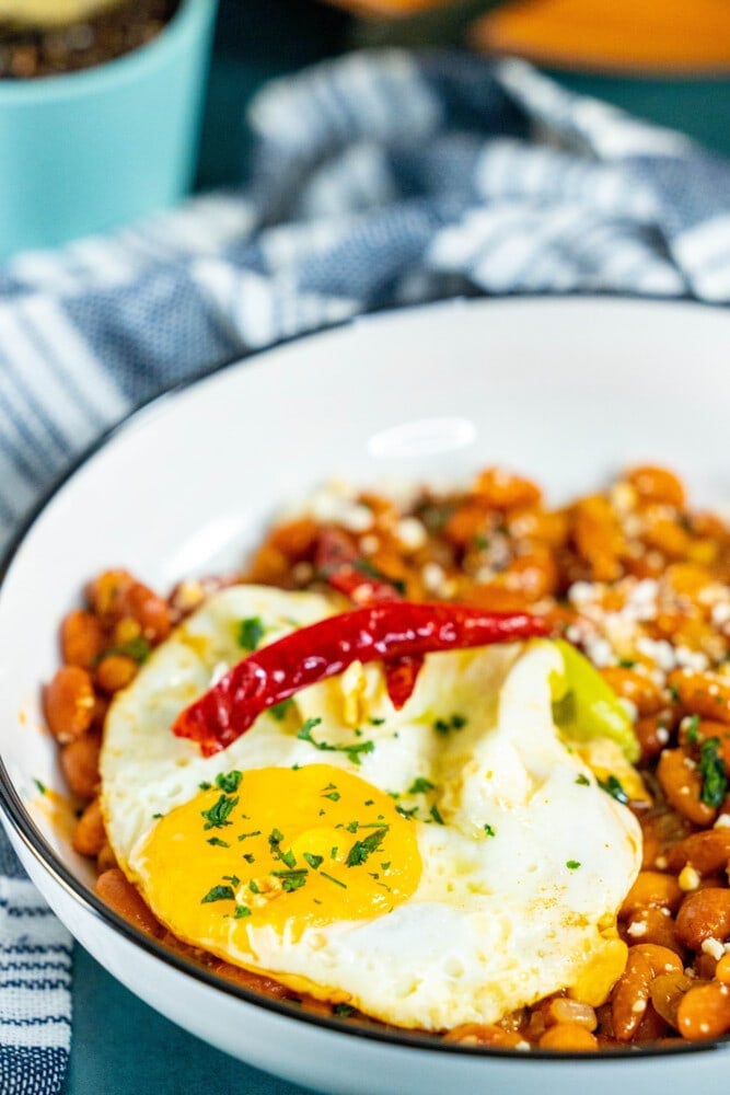 picture of huevos rancheros in a bowl on a table with a fried egg on top and chips in the bowl