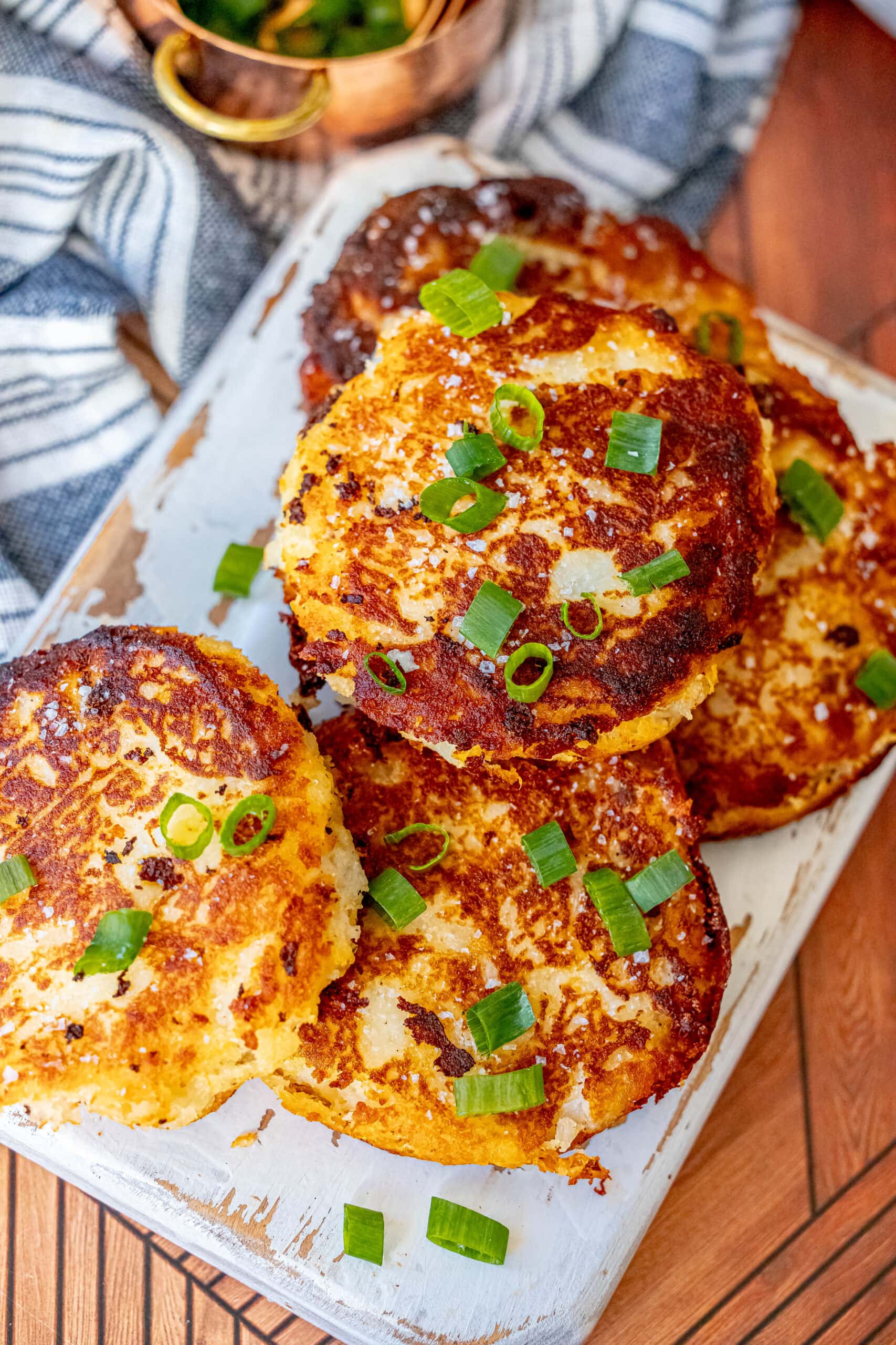 Irish potato pancakes with green onions on a white plate.