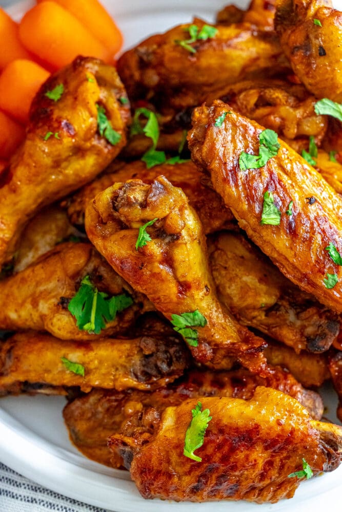 picture of tinga chicken wings on a white plate in front of a slow cooker