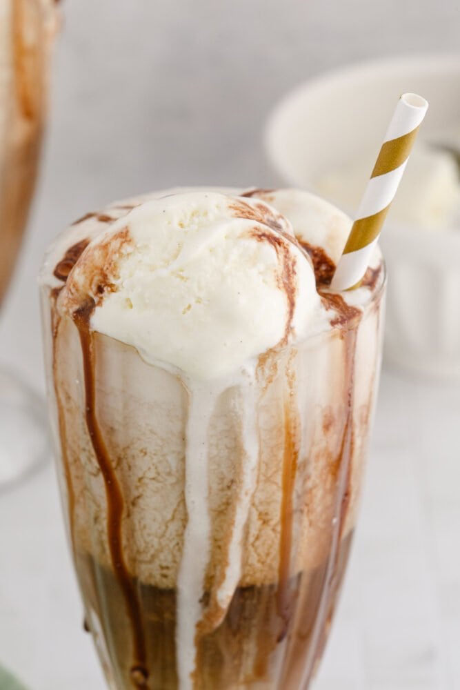 picture of guinness float in a a glass with a gold paper straw in it and chocolate syrup in the glass