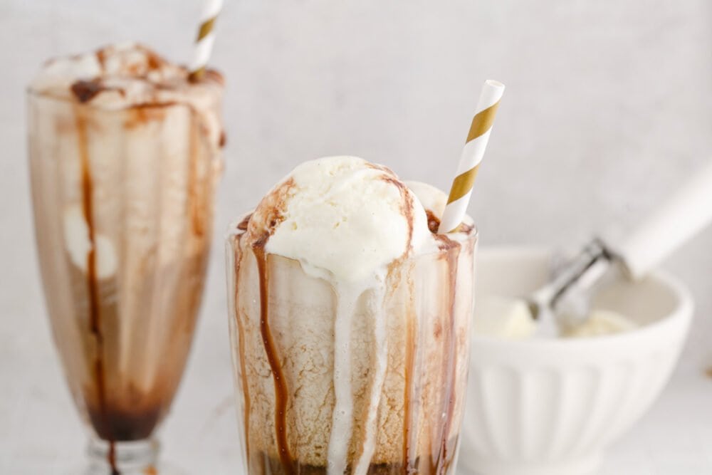 picture of guinness float in a a glass with a gold paper straw in it and chocolate syrup in the glass
