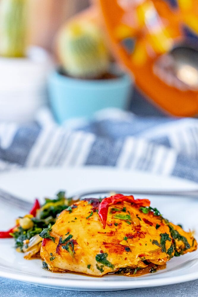 picture of harissa chicken and spinach on a white plate