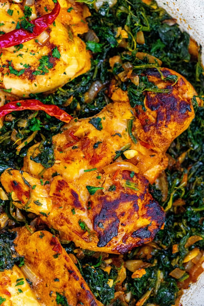 picture of harissa chicken in spinach in a pan 
