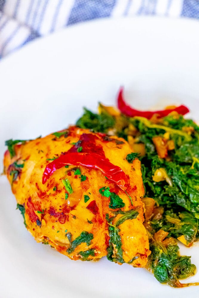 picture of harissa chicken in spinach on a white plate