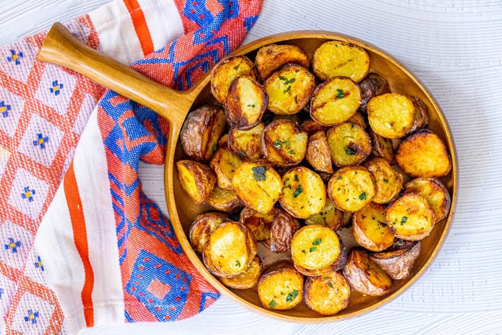 picture of grilled potatoes in a wood platter topped with herbs and salt
