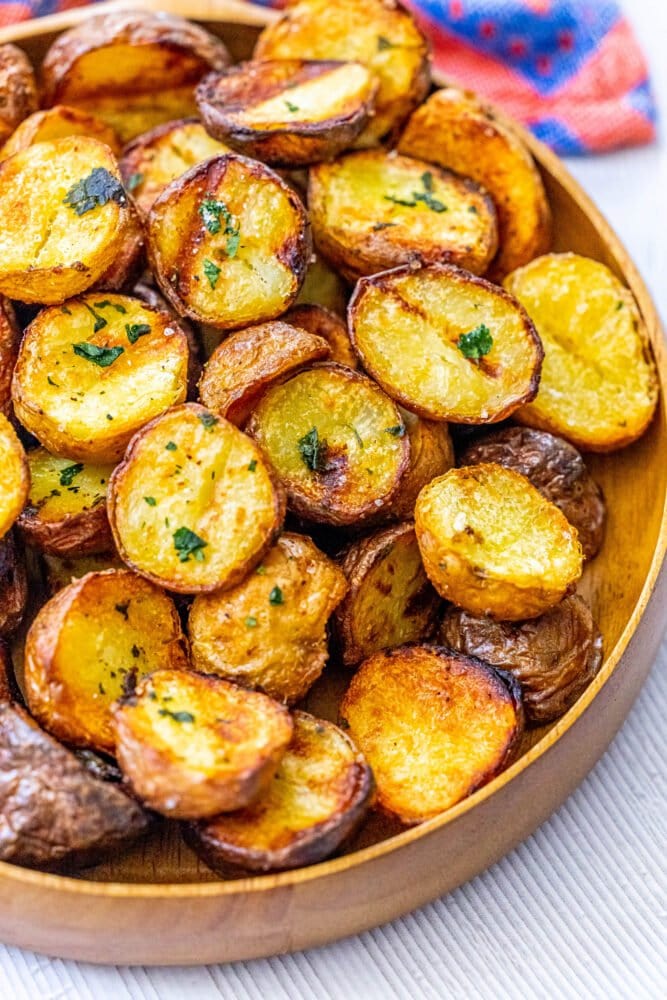picture of grilled potatoes in a wood platter topped with herbs and salt