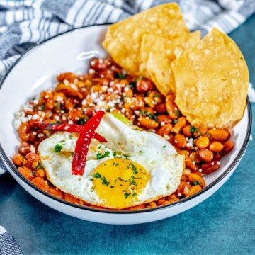 picture of huevos rancheros in a bowl on a table with a fried egg on top and chips in the bowl