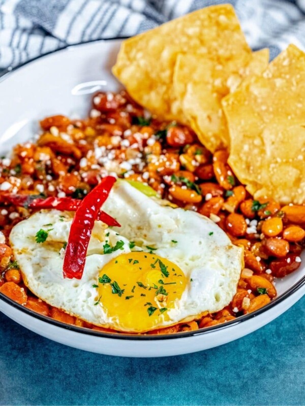 picture of huevos rancheros in a bowl on a table with a fried egg on top and chips in the bowl
