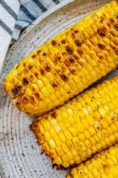 Grilled corn on the cob served on a plate.
