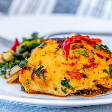 picture of harissa chicken and spinach on a white plate