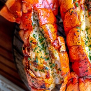 lobster tails with parsley and butter on them on a board