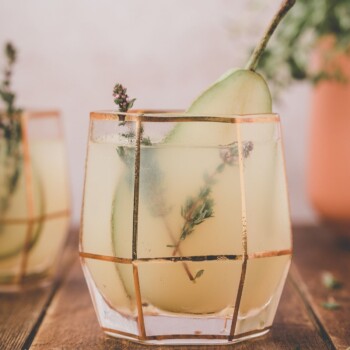 two cocktails with a slice of pear and herbs as a garnish