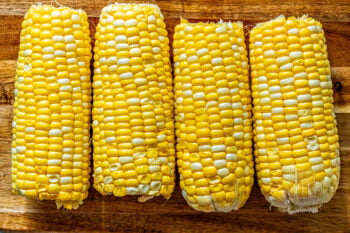 The best grilled corn on the cob recipe displayed with four ears of corn sitting on a wooden cutting board.