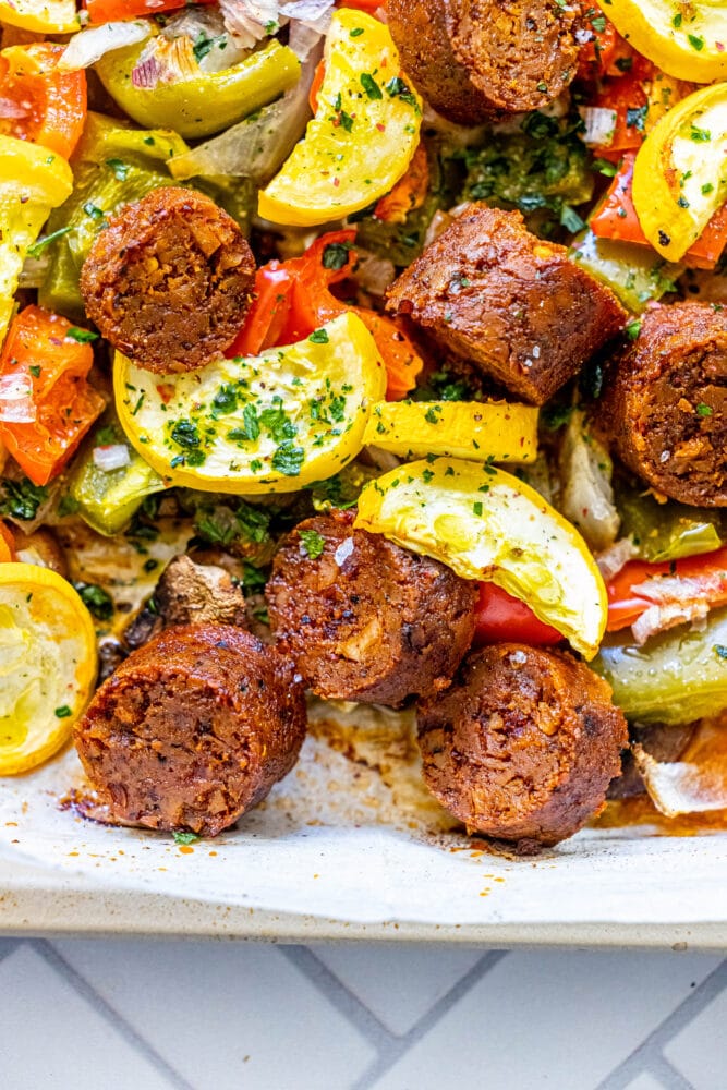 picture of baked vegan chorizo sausage, squash, peppers, onions, and mushrooms on a baking sheet