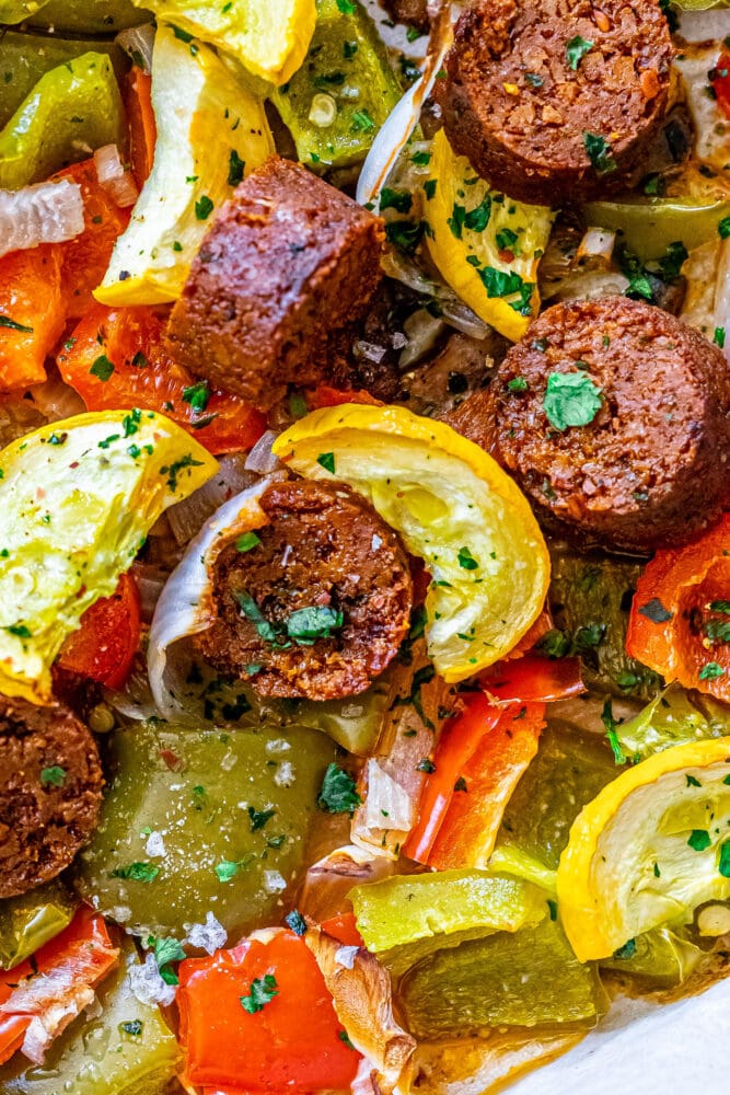 picture of baked vegan chorizo sausage, squash, peppers, onions, and mushrooms on a baking sheet