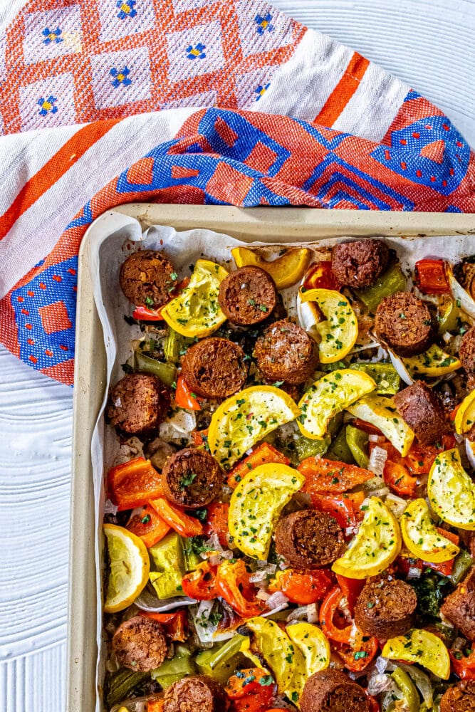 picture of baked vegan chorizo sausage, squash, peppers, onions, and mushrooms on a baking sheet