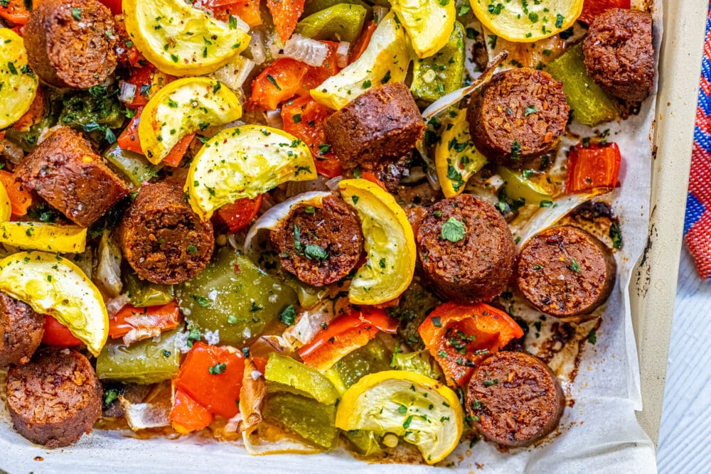 picture of baked vegan chorizo sausage, squash, peppers, onions, and mushrooms on a baking sheet
