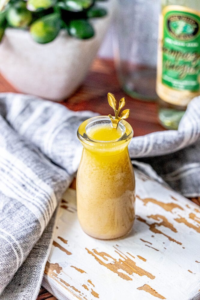 picture of champagne vinaigrette in a bottle with a gold spoon in it