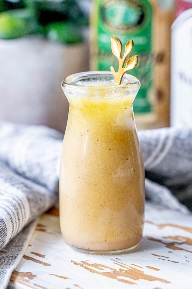 picture of champagne vinaigrette in a bottle with a gold spoon in it