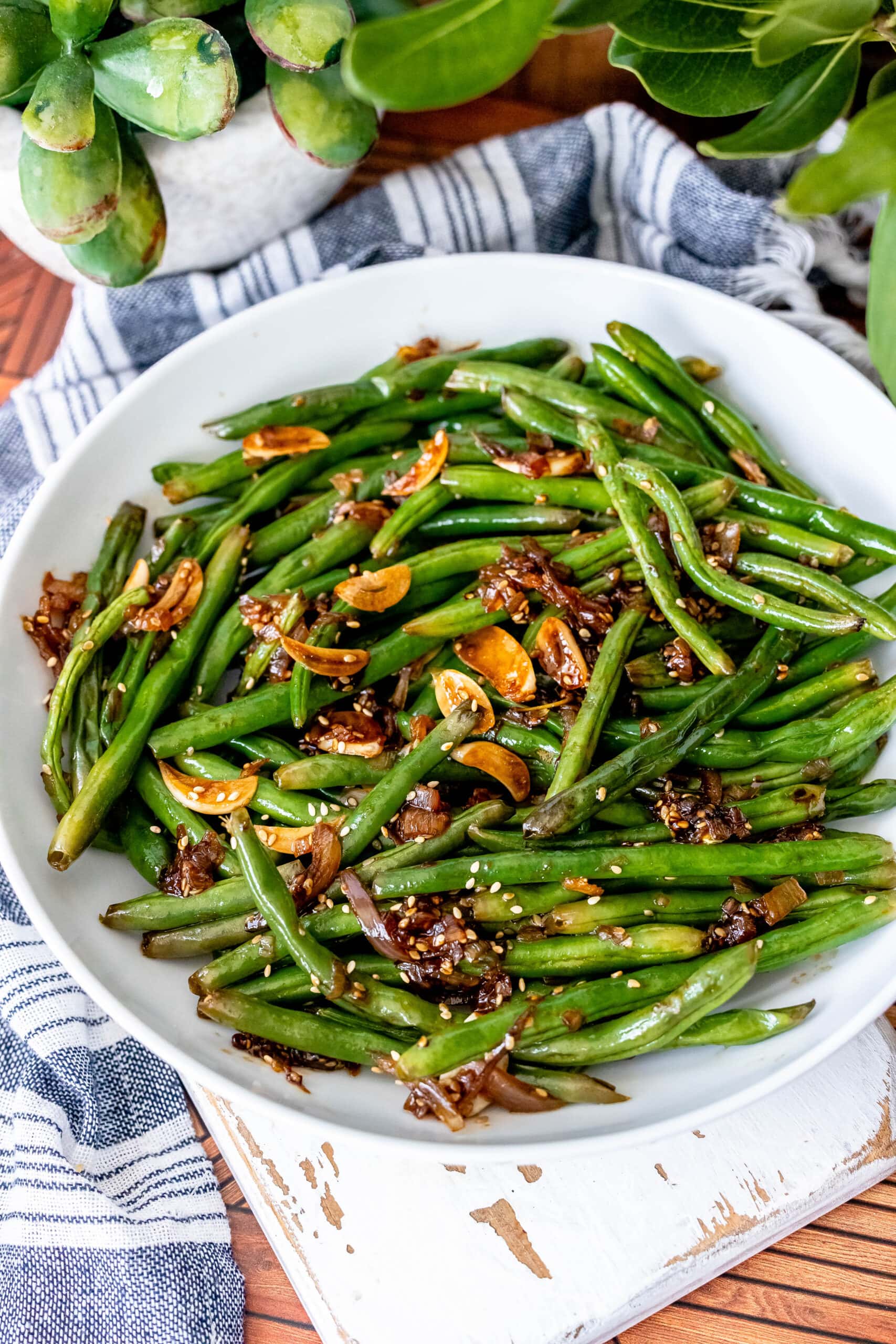 Green beans in a white bowl sprinkled with sesame seeds, inspired by the Chinese green beans recipe.