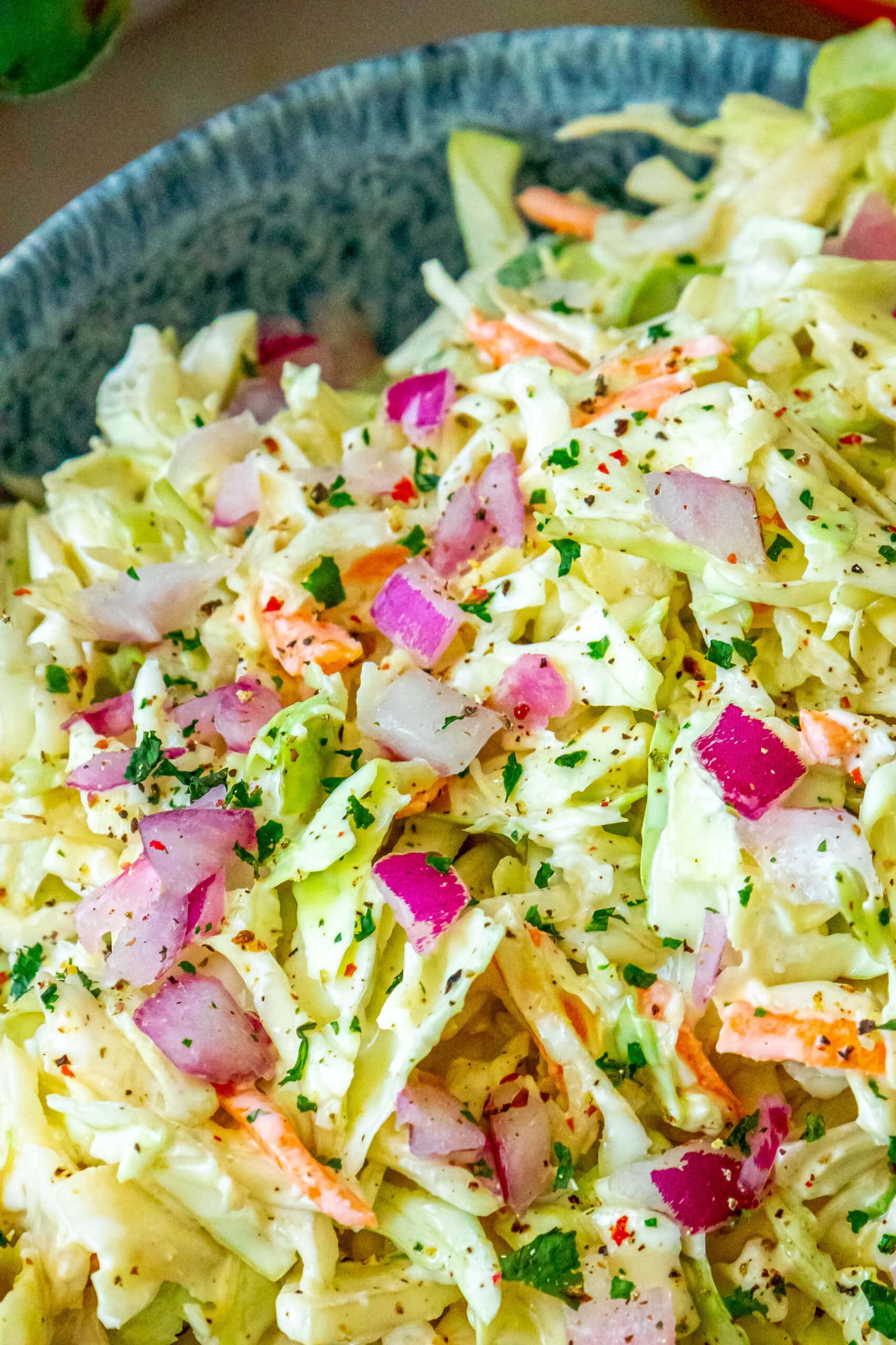 The Best Easy 4 ingredient coleslaw recipe in a bowl with onions and peppers.