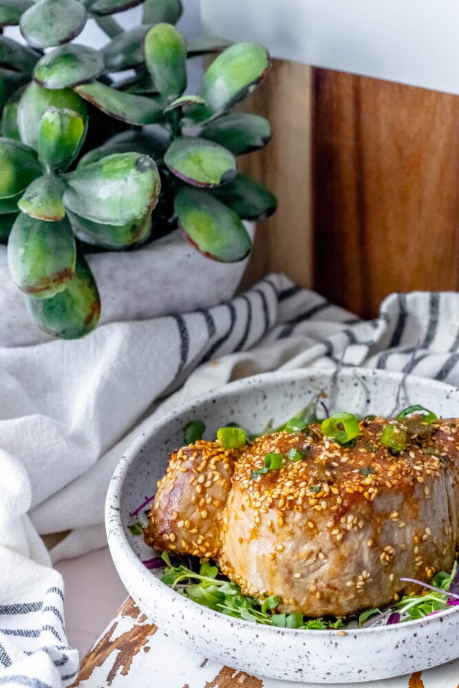 picture of tuna steak on a white plate topped with sesame seeds and green onions