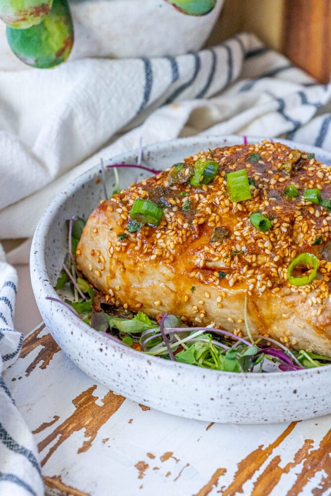 picture of tuna steak on a white plate topped with sesame seeds and green onions