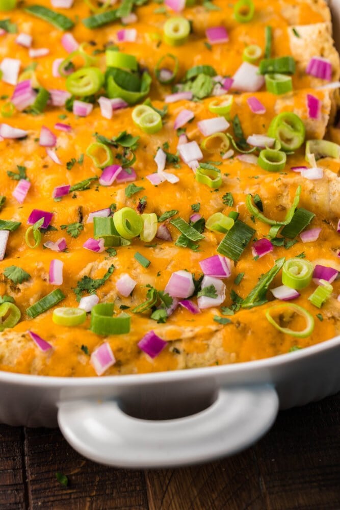picture of keto enchilada casserole in a white dish topped with cheese and onions