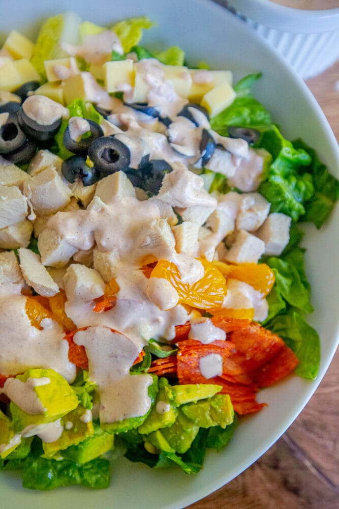 picture of aspen village salad with lettuce, chicken, mandarin oranges, olives, cheese, pepperoni, avocado, and southwestern dressing in a bowl 