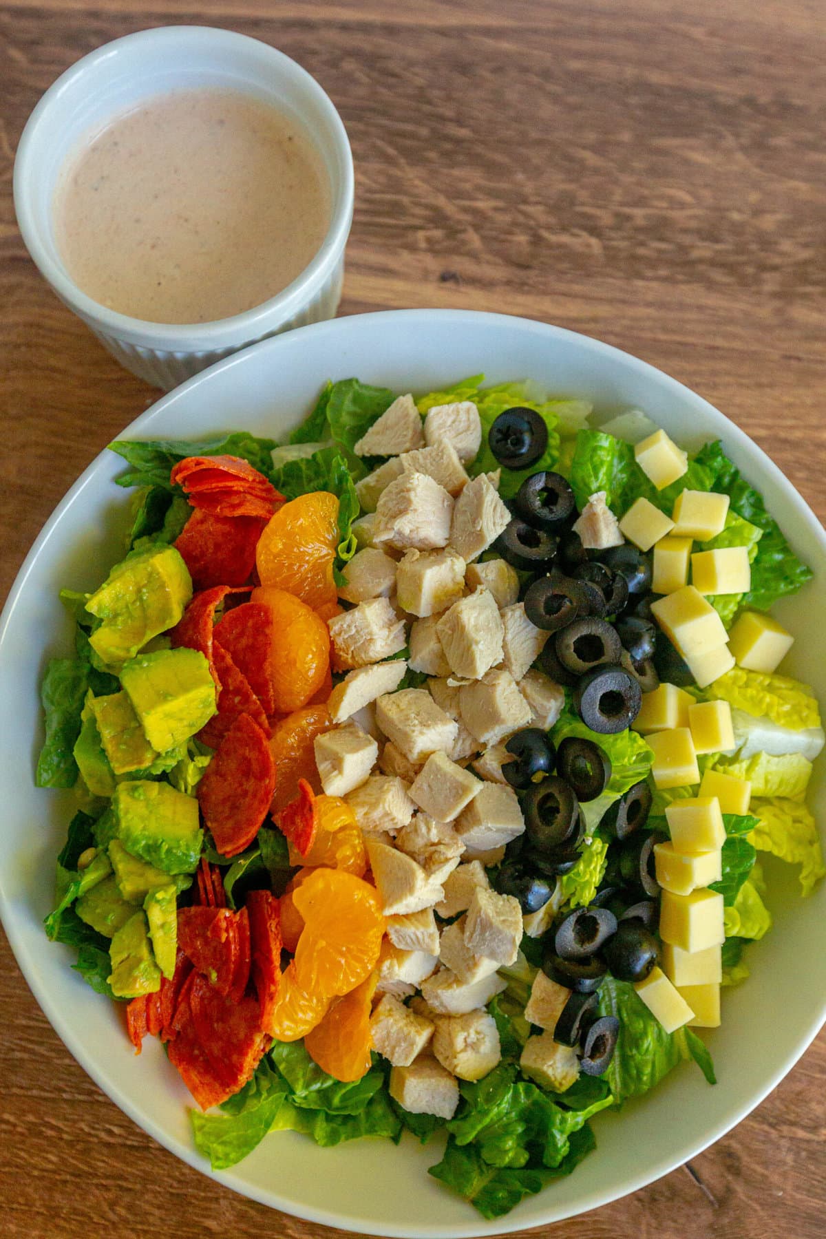 picture of aspen village salad with lettuce, chicken, mandarin oranges, olives, cheese, pepperoni, avocado, and southwestern dressing on a table