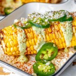 picture of elotes corn cob with crema, cheese, jalapenos, and spices on top