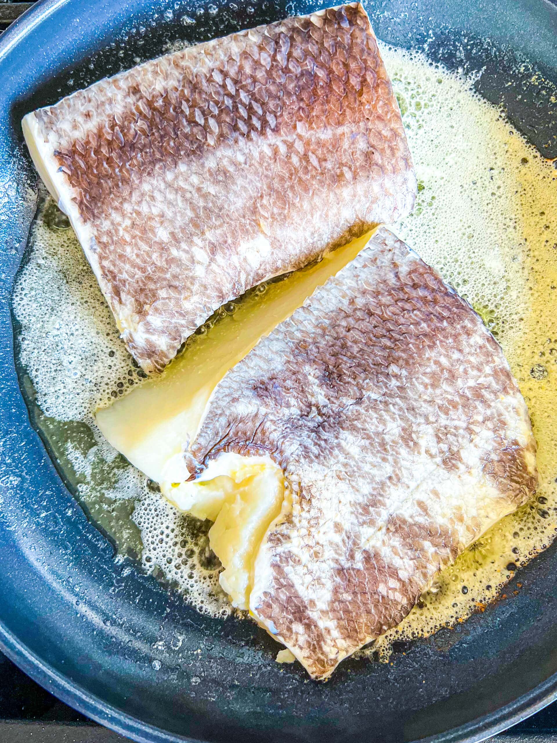 picture of chilean seabass pan frying in butter on the stove