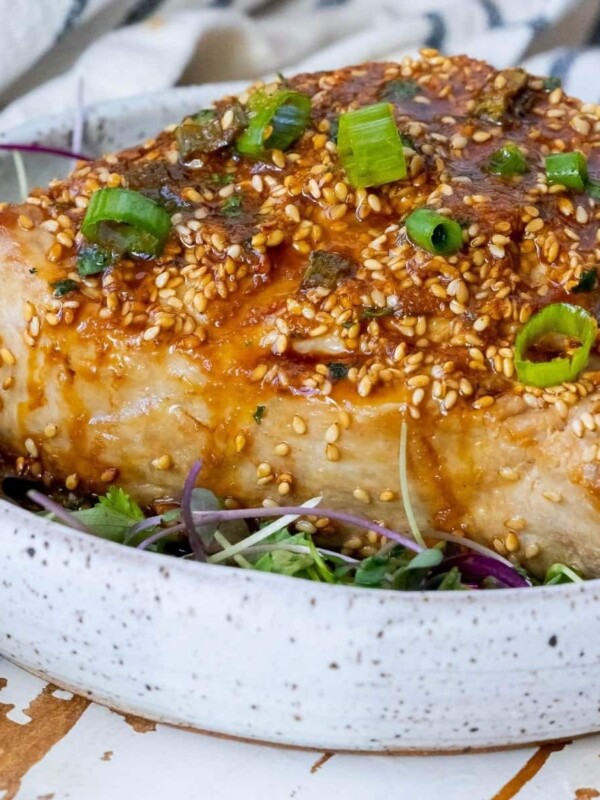picture of tuna steak on white plate with sesame seeds and sauce on top