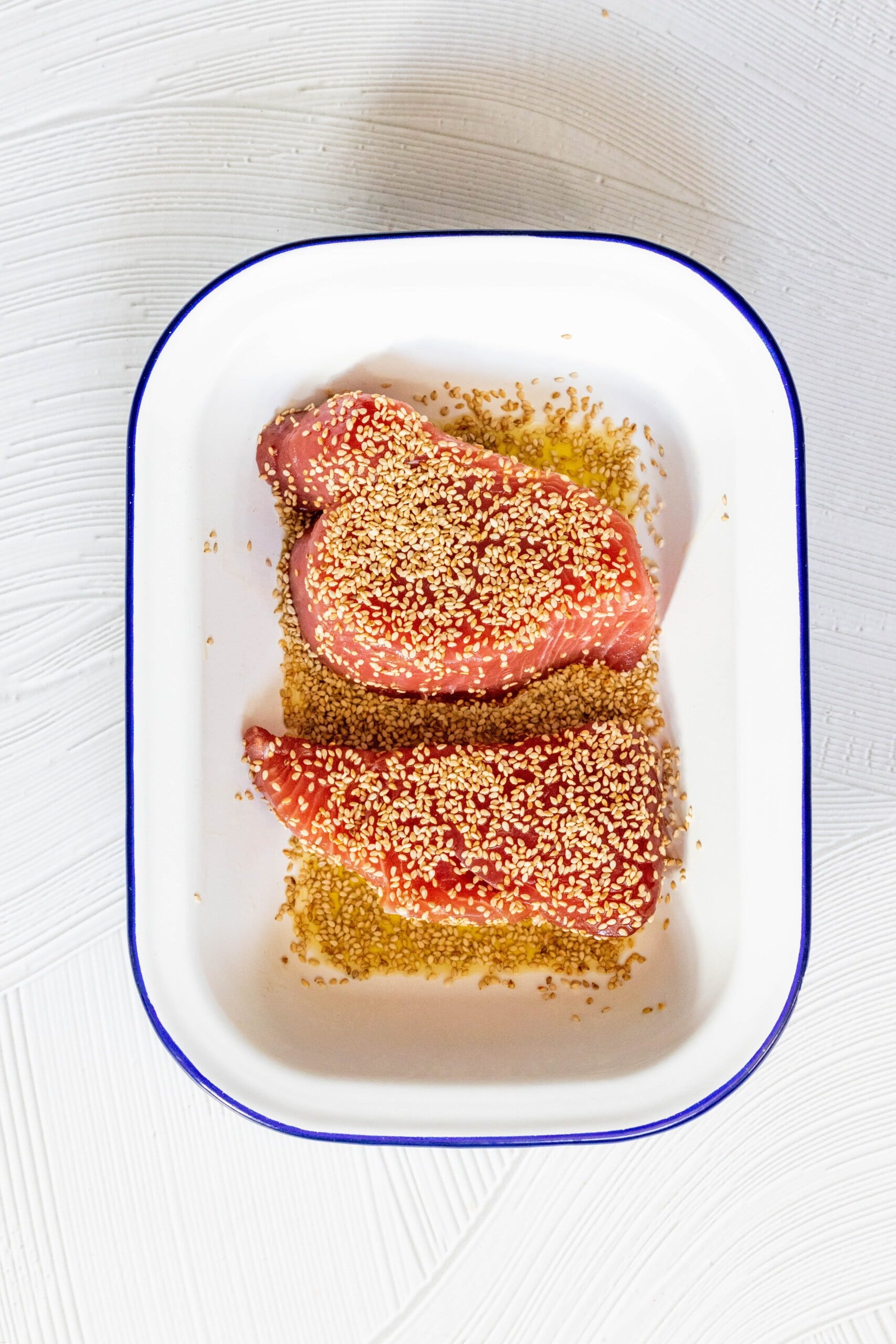 picture of tuna steaks marinating with sesame seeds covering the tuna in a bowl