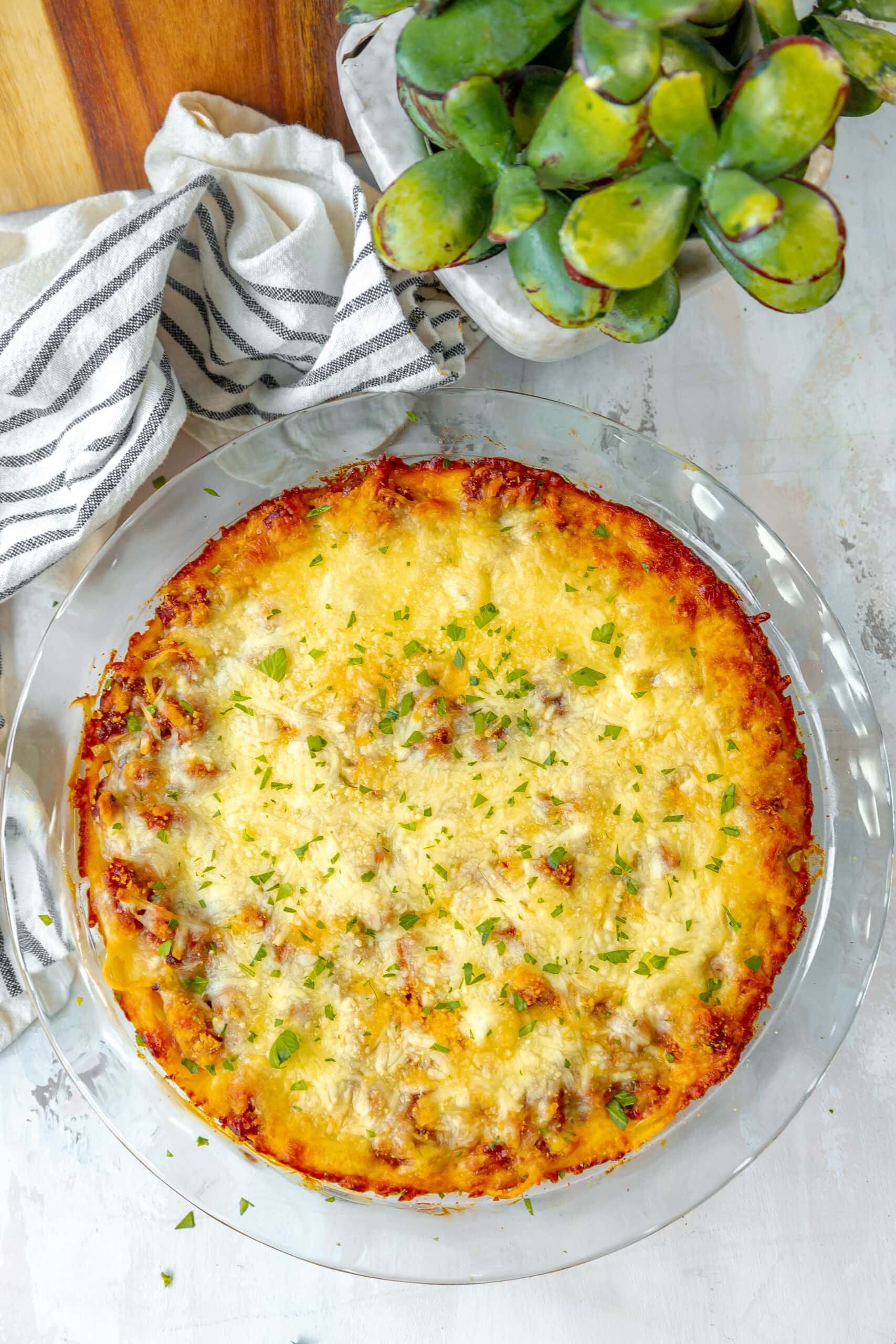 A cheesy pie with greens on a white plate.